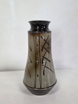 un vase noir et marron posé sur une table blanche