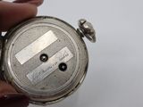 a person holding a silver pocket watch in their hand