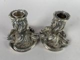two silver candlesticks sitting on a white surface