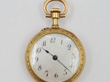 une montre de poche en or sur une surface blanche