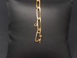 a gold plated bracelet with a link on a black pillow