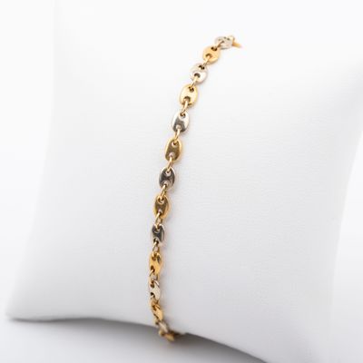 un bracelet en or orné de diamants noirs et blancs, présenté sur un coussin blanc