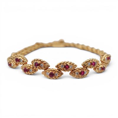 un gros plan sur un bracelet en or orné de pierres rouges et blanches
