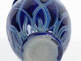 a blue vase sitting on a white surface with a white background