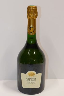 bottle of champagne on a white table with a white wall in the background
