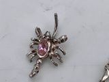 a silver necklace with a heart and a spider on it