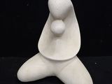 a white ceramic sculpture of a woman sitting on a black surface