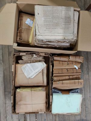 une boîte remplie de livres et de papiers posée sur un plancher en bois