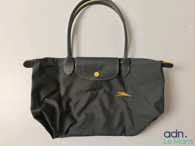 a black longchamp bag sitting on top of a white table