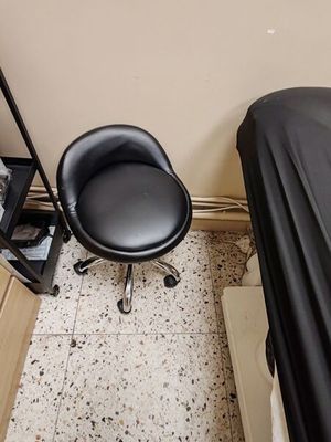 une chaise noire placée dans une pièce, à côté d'un lit