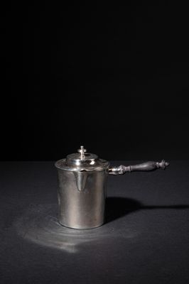 a small silver pot with a handle on a table