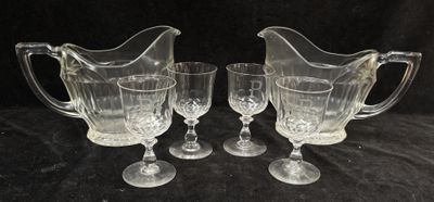trois pichets en verre transparent et deux verres à vin posés sur une nappe noire