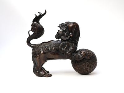 a bronze statue of a lion on a ball