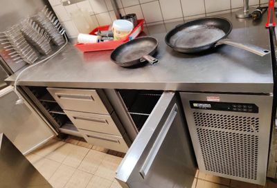 plan de travail en acier inoxydable dans une cuisine professionnelle, avec deux poêles et un lave-vaisselle