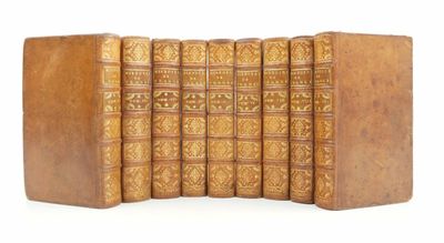six old books are lined up in a row on a white surface