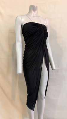 Le mannequin porte une robe noire à jupe drapée.