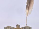 une plume posée sur un support dans lequel se trouve une autre plume