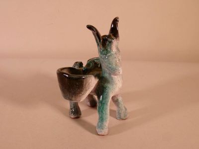 a ceramic animal that is holding a bowl in it ' s mouth