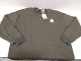 a brown shirt with a tag on it sitting on a bed