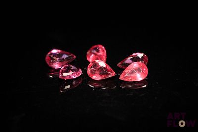 a group of three pink diamonds sitting on top of a black surface
