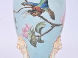 un vase orné d'un oiseau peint, posé sur un socle