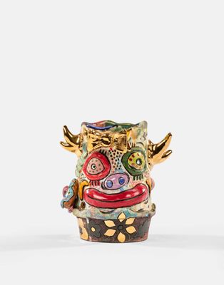 un gros plan d'un vase posé sur une surface blanche, avec un fond blanc