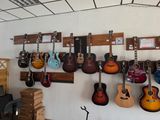 many guitars hanging on the wall in this room