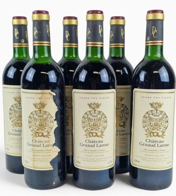 six bottles of wine are lined up in a row on a white surface