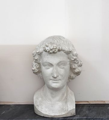 un buste en marbre représentant un homme aux cheveux bouclés, posé sur une table