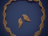 a gold necklace and earrings with leaves on a blue background