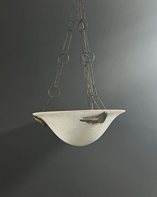 a white bowl hanging from a chain on the wall