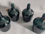 three green glass bottles with tags on them sitting on a white surface