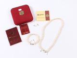 a red case with a pearl necklace, passport, and other items on a white surface