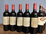 six bottles of wine are lined up on a wooden table