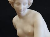 statue of a woman kneeling on a marble base with a black background