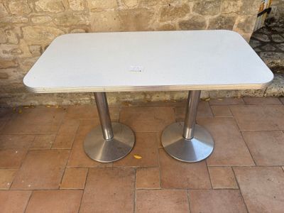 a white table with two silver pedestals on the ground