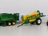 four toy tractors and a trailer on a white surface