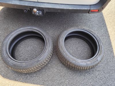 deux pneus posés par terre à côté d'une voiture dans la rue