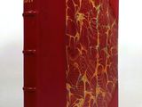an old red book sitting on top of a table next to a white wall