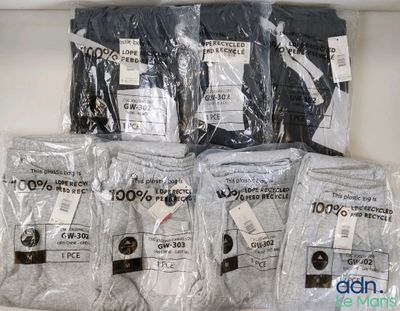 plusieurs sacs de t-shirts posés sur une étagère, avec leurs étiquettes de prix