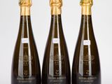 trois bouteilles de champagne posées les unes à côté des autres sur une surface blanche
