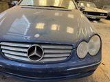 a blue mercedes parked in a garage with other cars in the background