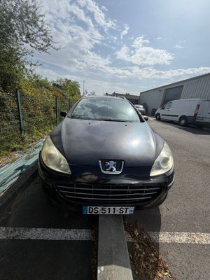 une voiture noire garée dans un parking à côté d'un bâtiment