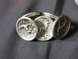 two silver rings with a coin on top of them sitting on a table