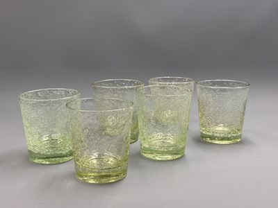 quatre verres verts posés sur une table blanche