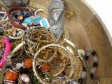 a wooden bowl filled with lots of jewelry on a table