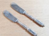 two silverwares on a wooden table with a knife and fork