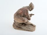 a small statue of a man sitting on a rock