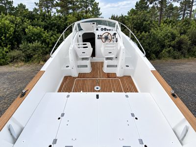 a white boat with a wooden deck in the middle of the road