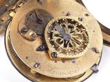 a close up of a pocket watch on a white surface